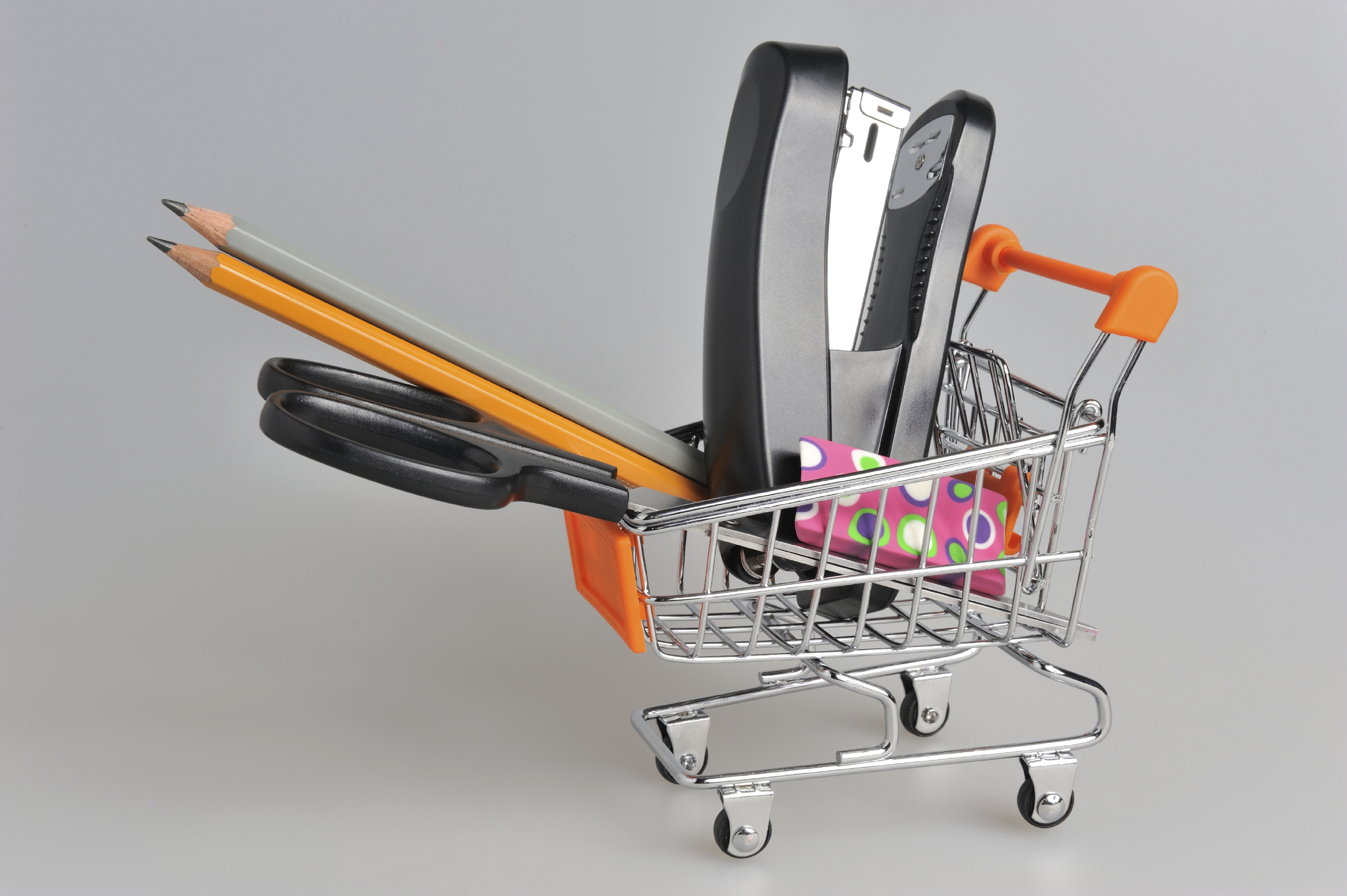 Shopping cart and stationery within on gray background