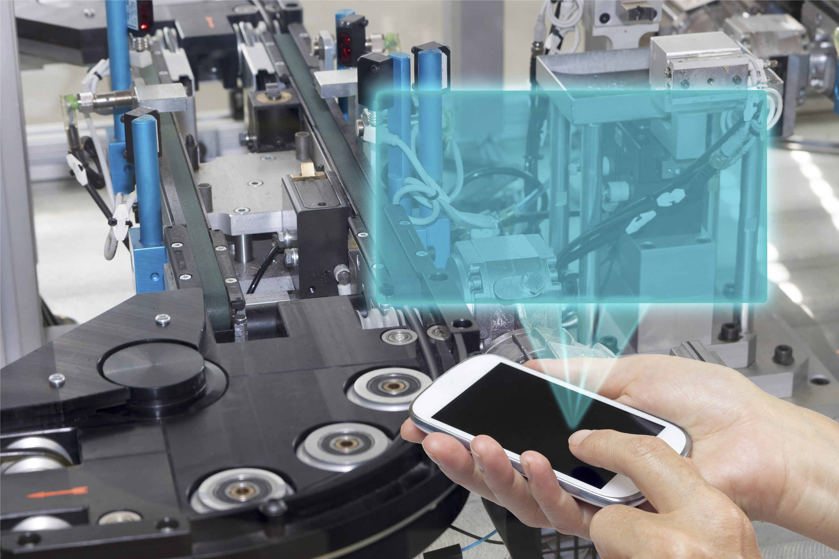 Female is holding the smart phone Blank transparent rectangle radiates from the screen smart phone. The rectangle is ready for your text. The automatic production line is in the background. All potential trademarks are rermoved.